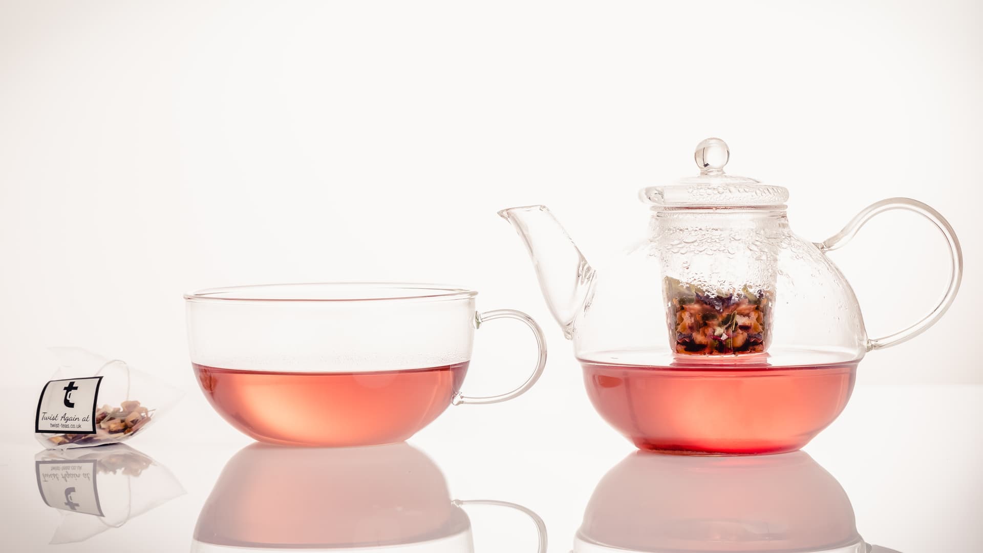 A glass teapot and cup of Twist tea brewing