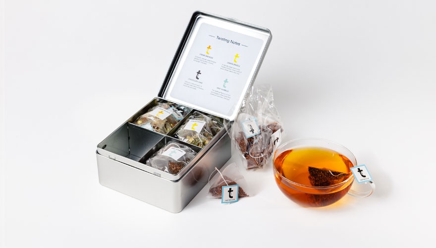 A rooibos tea latte beside the Tea Lattes tasting menu caddy