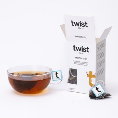 Brewdolph Christmas tea carton beside a cup of Brewdolph tea