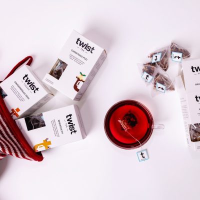Twist Christmas tea cartons spilling from a striped Christmas stocking beside a cup of tea