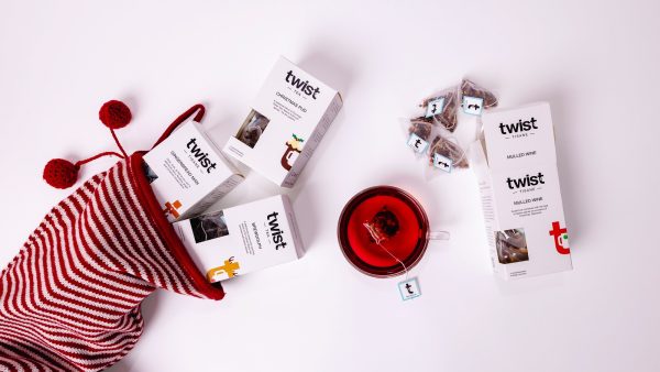 Twist Christmas tea cartons spilling from a striped Christmas stocking beside a cup of tea