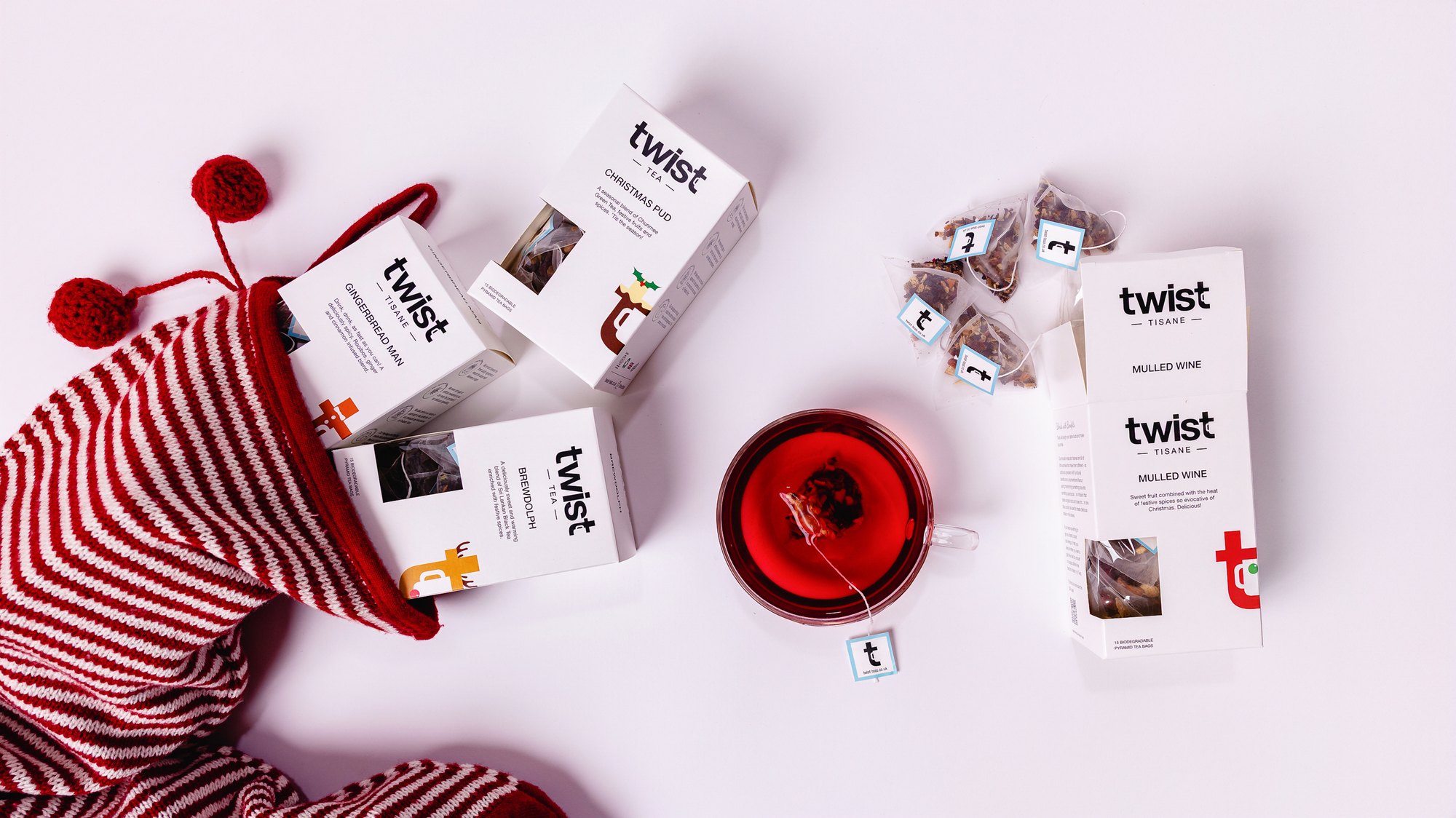 Twist Christmas tea cartons spilling from a striped Christmas stocking beside a cup of tea