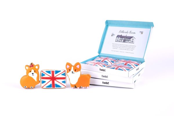 Hand-iced corgi and Union Jack gingerbread biscuits in front of three Twist biscuit boxes