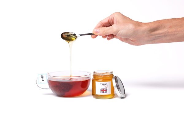 A spoonful of Pollards Farm honey drizzling into a cup of tea