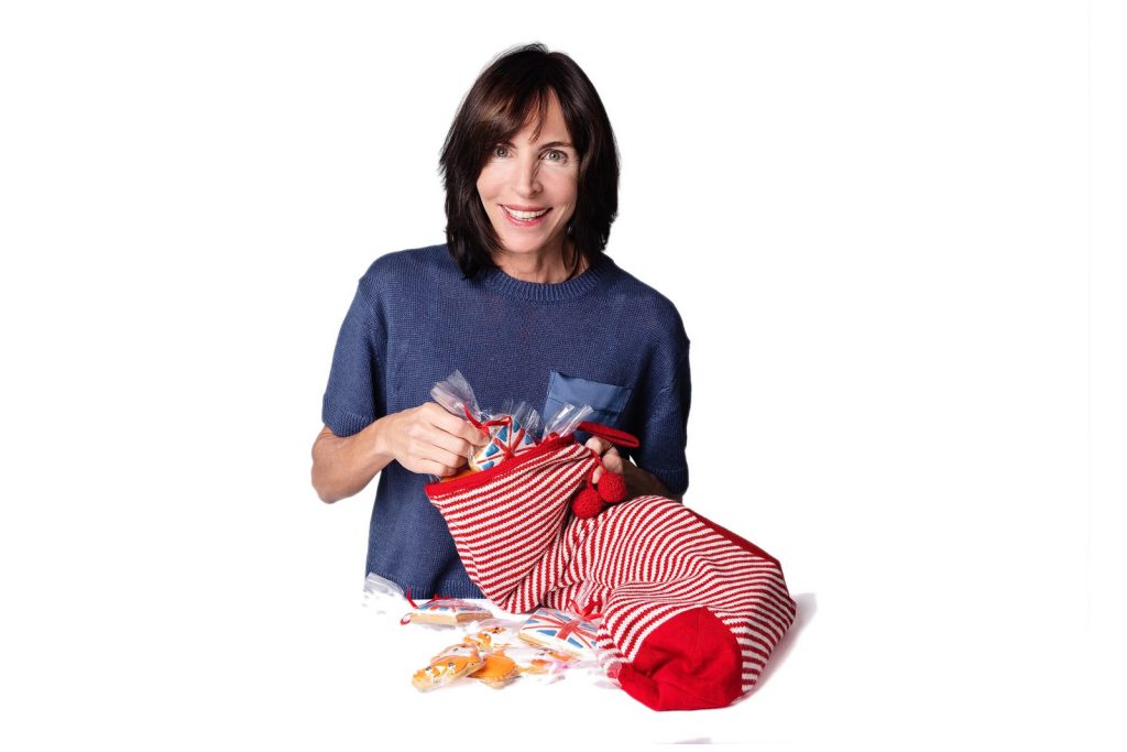 Claire filling a striped Christmas stocking with hand-iced gingerbread biscuits